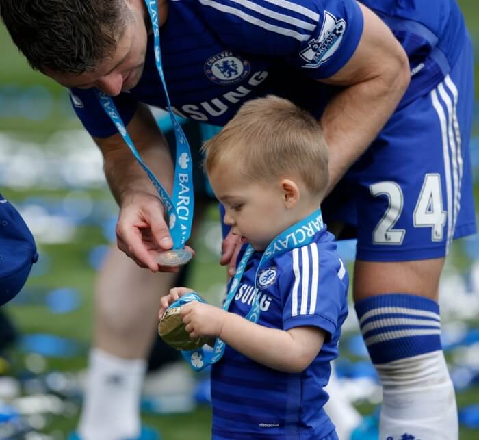 An image of Gary Cahill comparing his medal with his son Leo