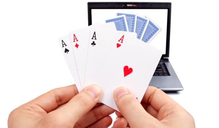 An image of poker in the hand and on a laptop screen - online poker